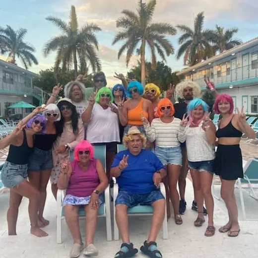 Guests in colourful wigs and swimwear at a beach party