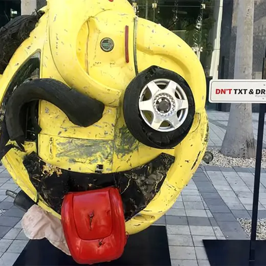 Crushed yellow car sculpture with a smiley face