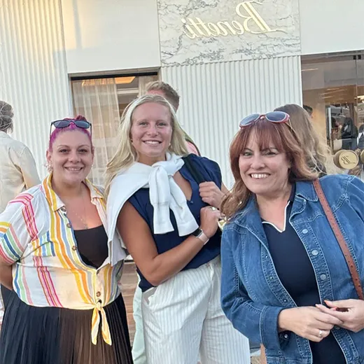 Three women posing at an event entrance