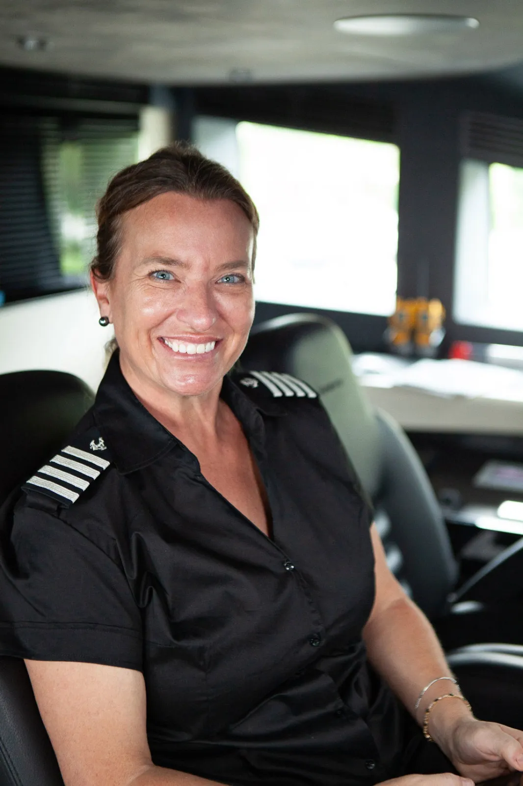 Captain Kelly Gordon smiling on the bridge of a superyacht, in uniform with captain's epaulettes