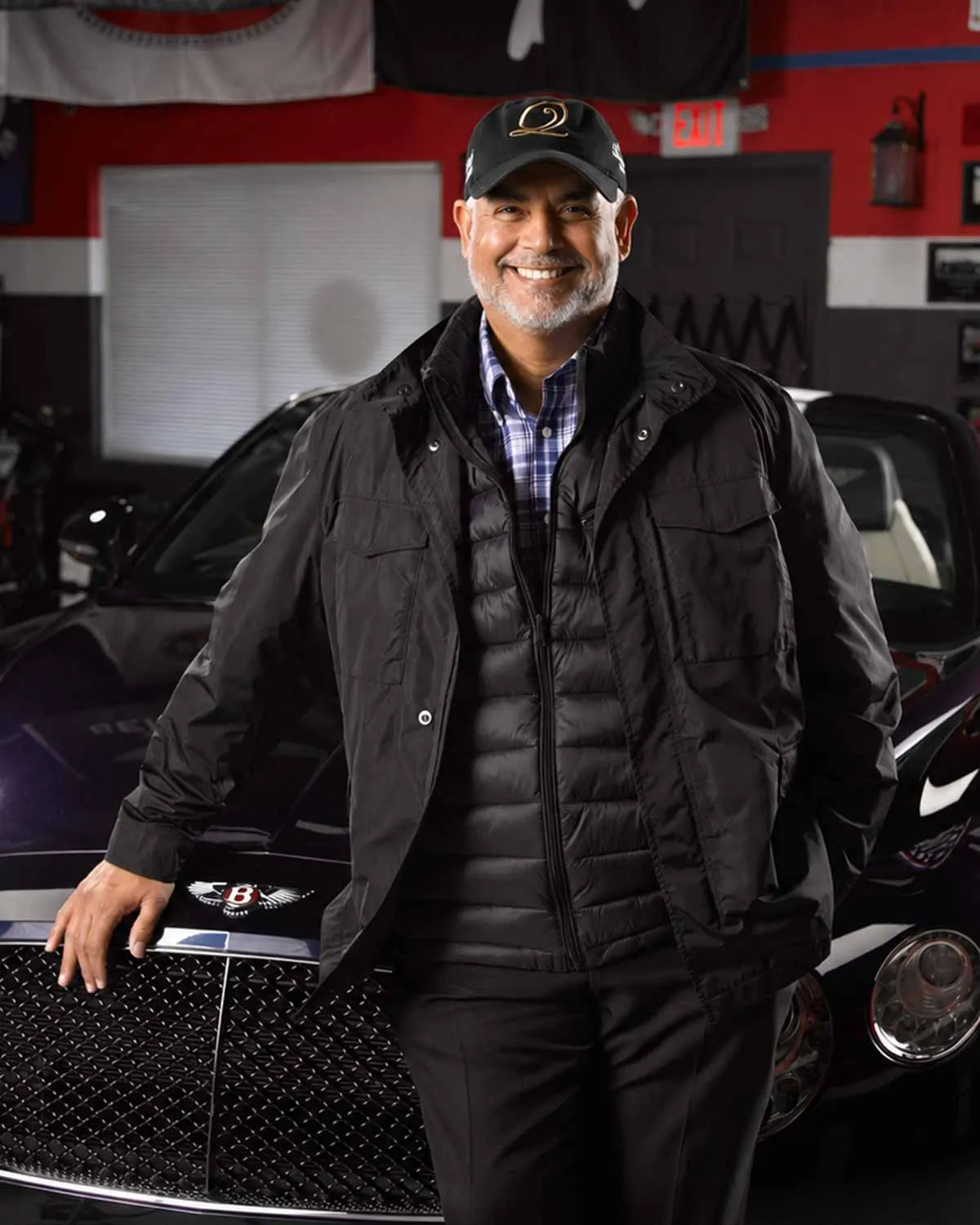 Patrick Knowles leaning on the grille of a Bentley in his garage